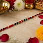 Traditional green beaded rakhi with golden accents and pearl-style beads