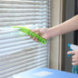 A person using the window blind cleaner brush with microfiber sleeves to dust white window blinds.